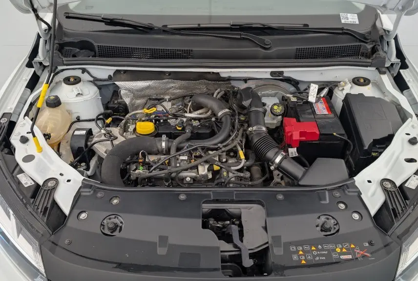 Vue plongeante sur le moteur de la Dacia Sandero blanc glacier 2022 avec capot ouvert et détails du compartiment moteur visible.