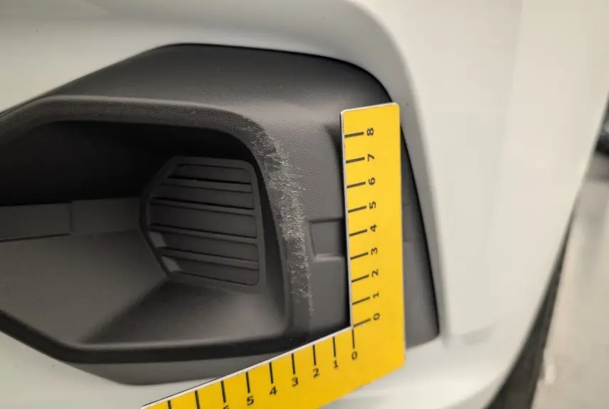 Gros plan sur l'entrée d'air avant droite noire avec rayures sur la carrosserie blanche d'une Dacia Sandero 2022.