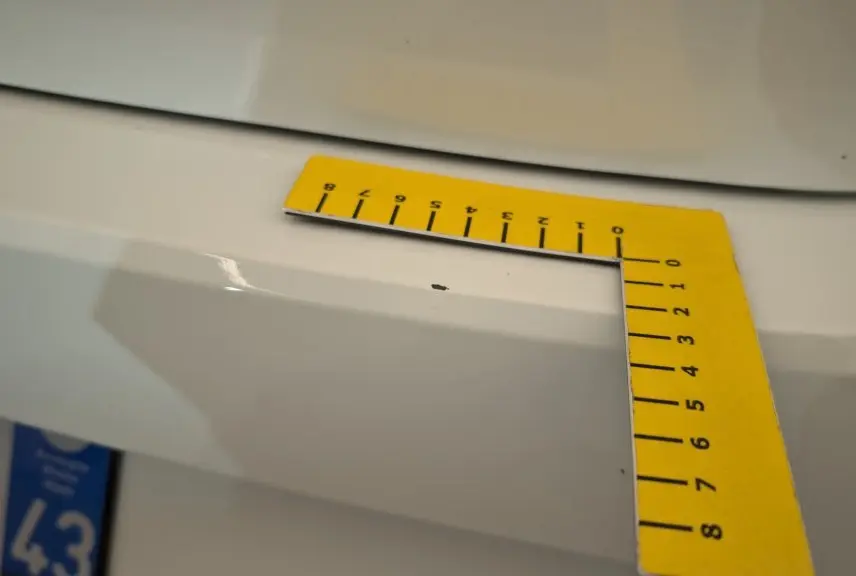 Gros plan sur une petite éclatation de peinture blanche sur le pare-chocs arrière d'une Dacia Sandero ECO-G 100 2022.