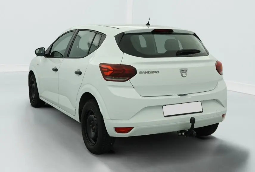 Vue 3/4 arrière droite d'une Dacia Sandero blanche avec attelage et feux arrière à signature lumineuse en Y.