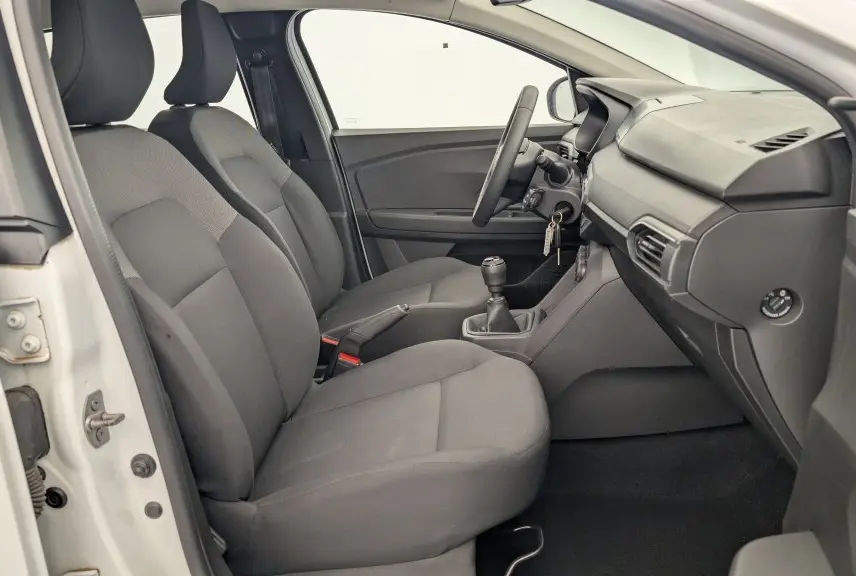 Intérieur côté conducteur de la Dacia Sandero ECO-G 100 2022, sièges gris et tableau de bord simple en vue latérale.