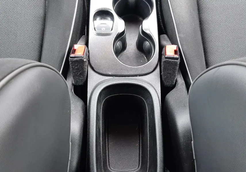 Vue plongeante sur la console centrale noire du Fiat 500X rouge, avec porte-gobelets et leviers de frein à main visibles.