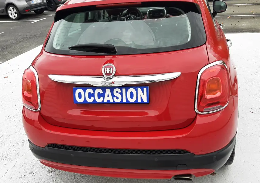 Vue arrière d'une FIAT 500X rouge avec plaque "OCCASION" sur un parking extérieur.