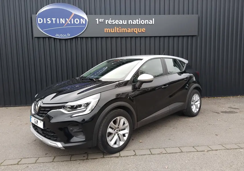 Renault Captur noir 3/4 avant droit avec toit blanc, stationné devant un mur noir avec enseigne Distinxion.