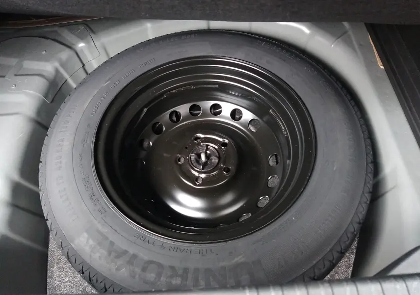 Gros plan sur la roue de secours noire logée dans le coffre d’un Renault Captur noir, version essence 2021.