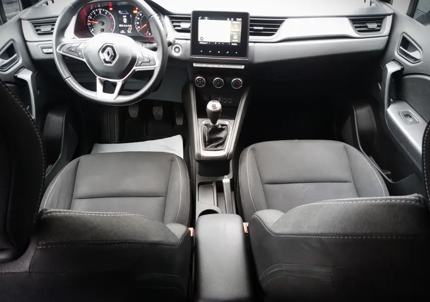 Vue intérieure avant du Renault Captur noir 2021, mettant en valeur le volant, la console centrale avec boîte manuelle et l'écran tactile.