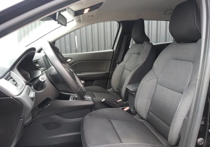 Vue intérieure côté conducteur du Renault Captur noir 2021, mettant en valeur les sièges tissu gris et la console centrale.