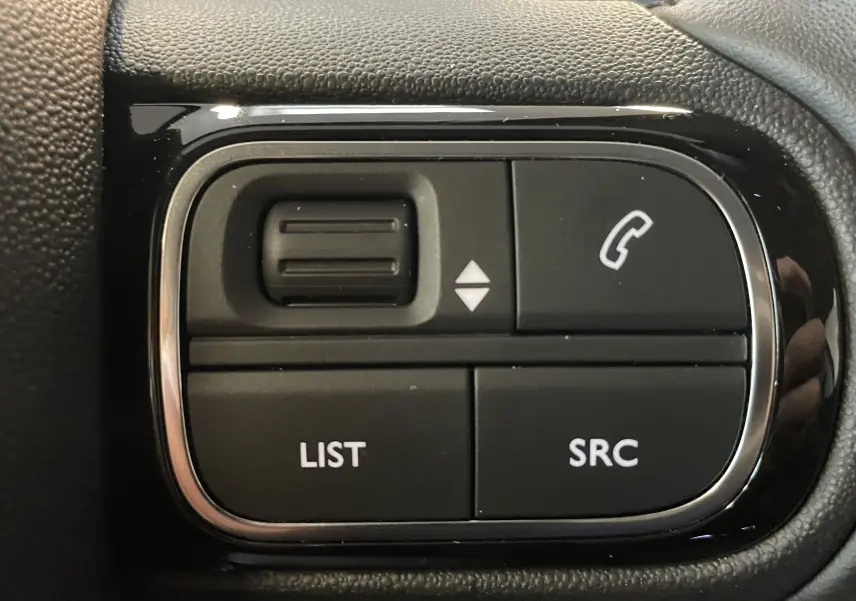 Gros plan sur les commandes noires du volant côté gauche du Citroën C5 Aircross 2024, avec boutons list, SRC et appel.