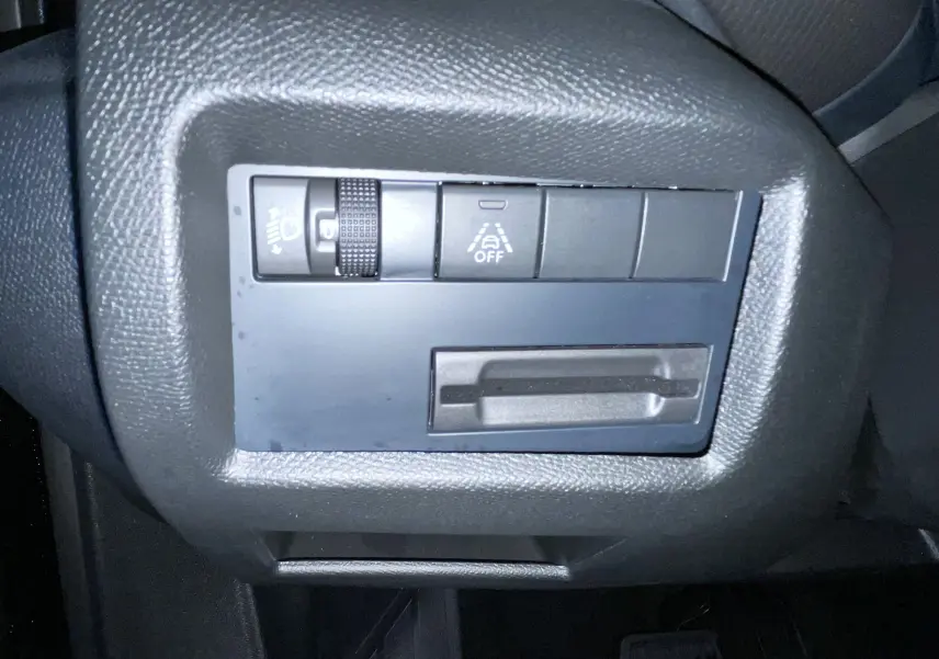 Gros plan sur les commandes de réglage des feux et assistance à la conduite du Citroën C5 Aircross 2024 noir.