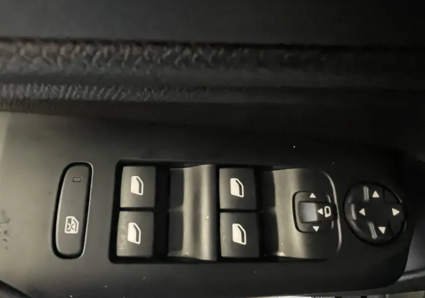 Gros plan sur les commandes des vitres électriques et réglages des rétroviseurs côté conducteur d’un Citroën C5 Aircross noir.