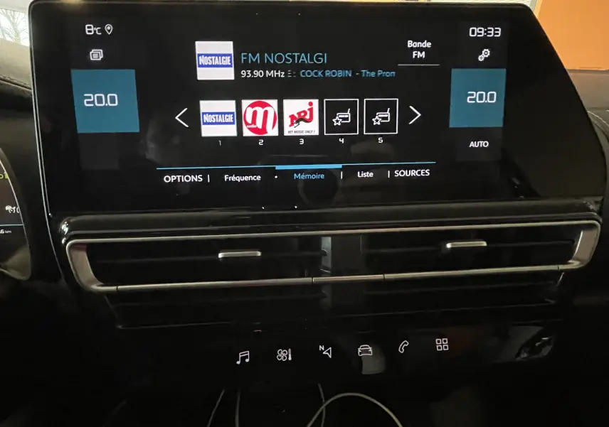 Écran tactile central du tableau de bord du Citroën C5 Aircross 2024 affichant la radio FM et la climatisation à 20°C.