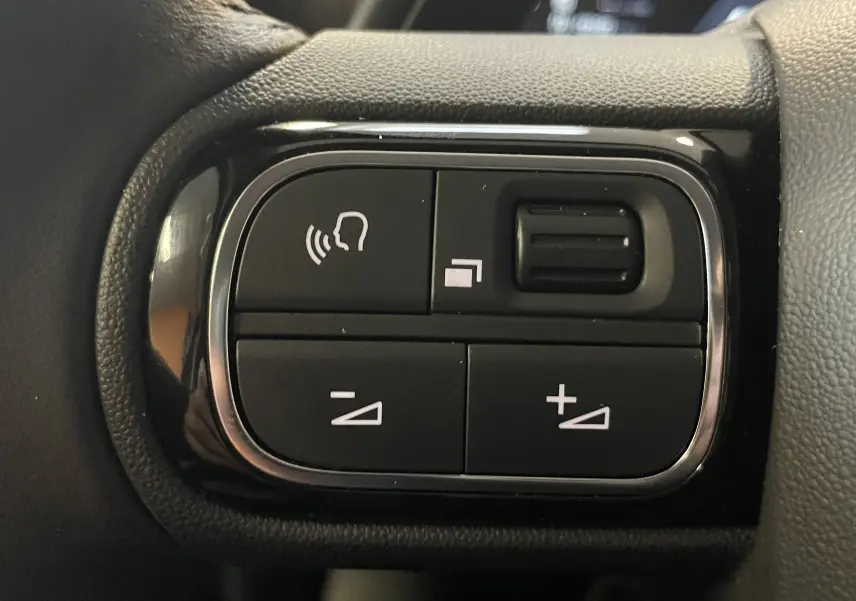 Gros plan sur les commandes au volant du Citroën C5 Aircross 2024 noir, avec boutons de réglage vocal et volume.
