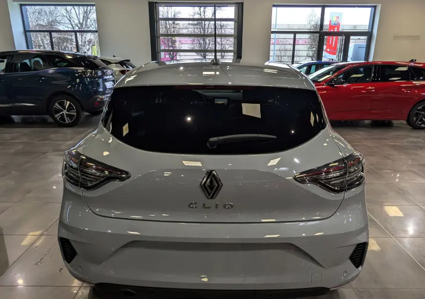 Vue arrière d'une Renault Clio V gris Rafale avec feux LED et vitre arrière teintée dans un showroom.