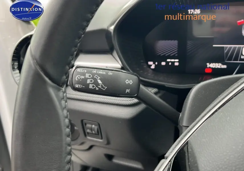 Gros plan sur le commodo gauche du volant cuir d'une Skoda Fabia blanche, affichage numérique en arrière-plan.