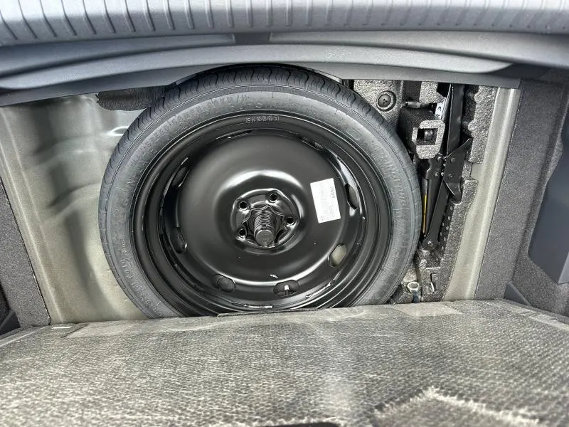 Roue de secours noire et cric dans le coffre d'un CUPRA Formentor 2.0 TDI 150ch V DSG7 noir Minuit métallisé, vue de dessus.