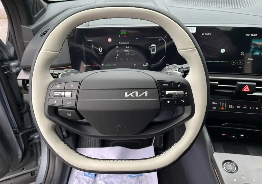 Vue intérieure centrée sur le volant cuir bicolore gris clair et noir du Kia Sportage 2026 avec tableau de bord numérique.