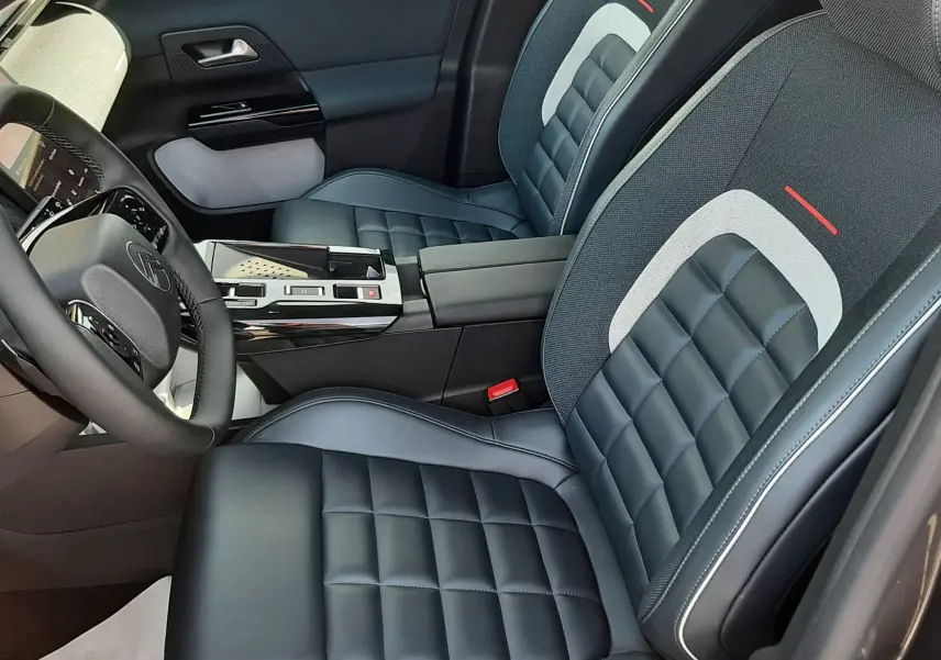 Intérieur avant du Citroën C5 Aircross hybride 2026, sièges cuir et tissu noir avec surpiqûres blanches et détails rouges.
