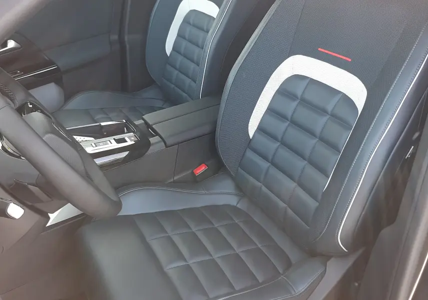 Vue intérieure côté conducteur du Citroën C5 Aircross hybride 2026, sièges noirs avec surpiqûres et détails gris clair.