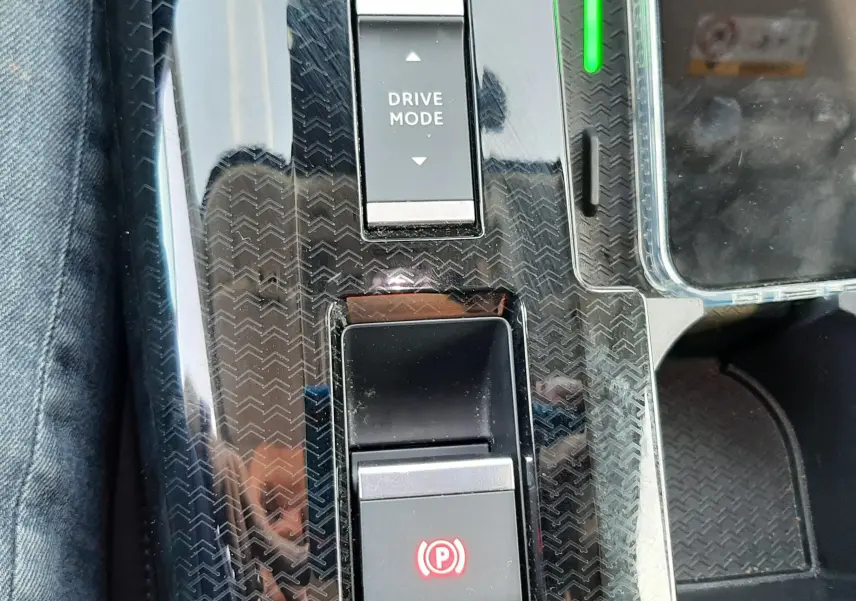 Gros plan sur la console centrale noire brillante du Citroën C5 Aircross hybride 2026 avec boutons Drive Mode et frein à main électronique.