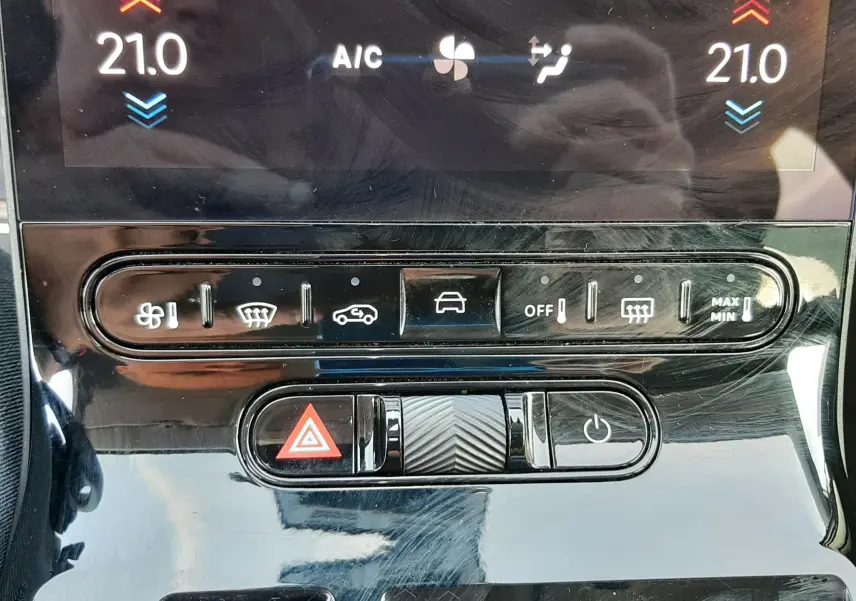 Gros plan sur la console centrale noire brillante du Citroën C5 Aircross Hybride 145ch, avec commandes climatisation et bouton hazard rouge.