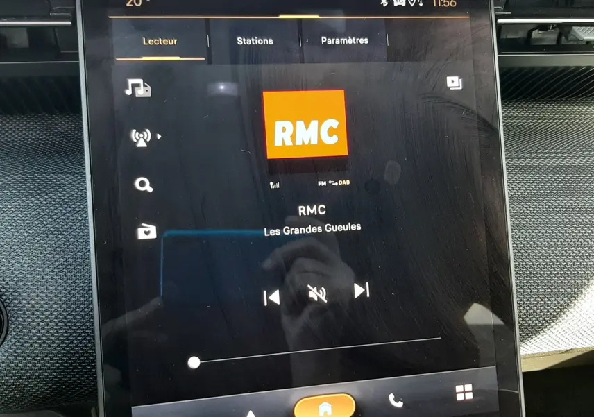 Écran tactile central du Citroën C5 Aircross hybride 2026 affichant la radio RMC, ambiance intérieure noire.