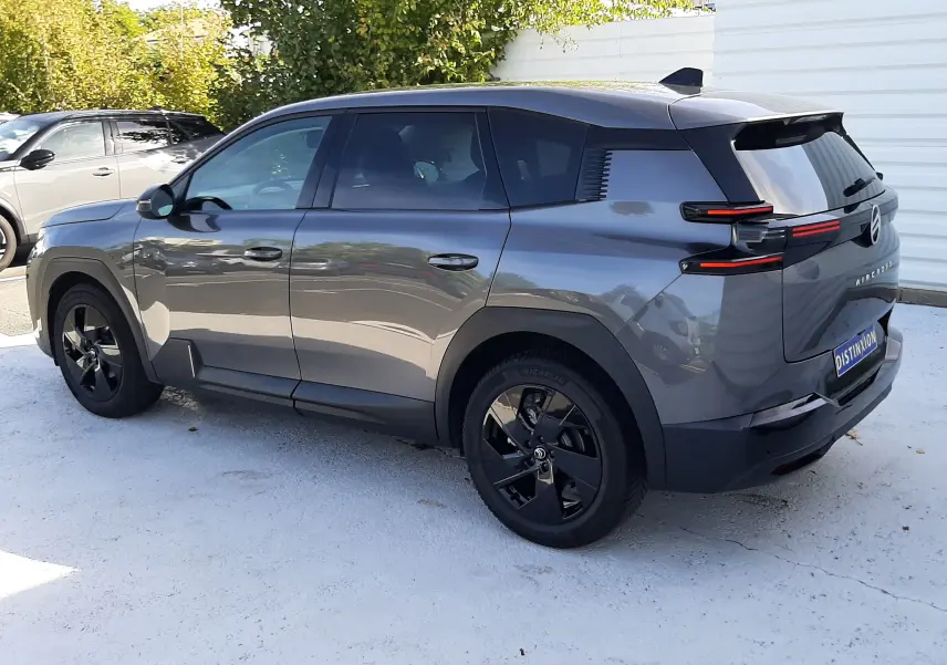 Vue 3/4 arrière droite d'un Citroën C5 Aircross hybride gris platinium avec jantes noires et feux arrière LED distinctifs.