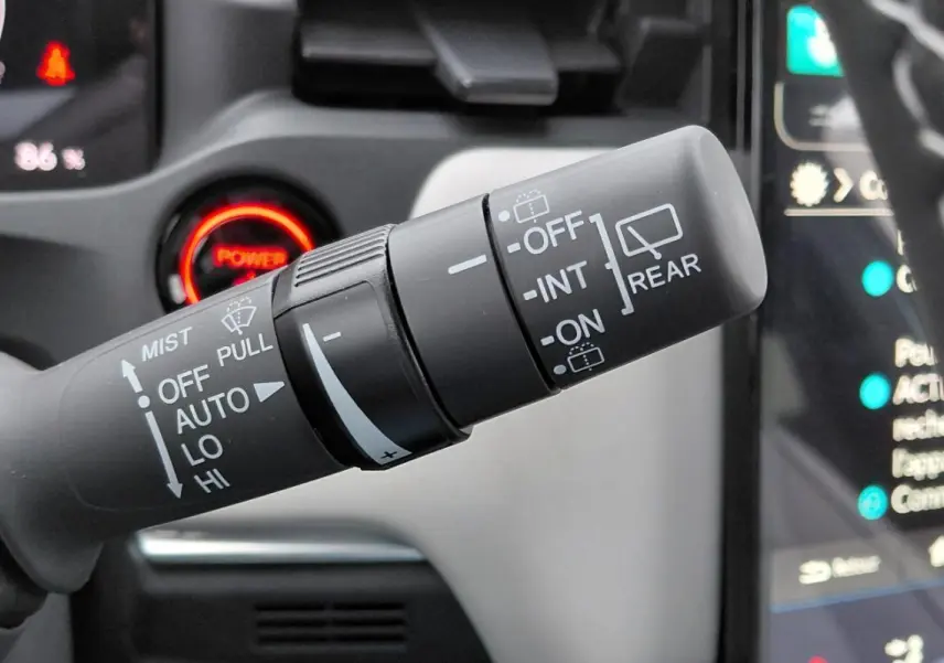 Gros plan sur la commande des essuie-glaces du Honda e:Ny1 204 ch Advance 2025, intérieur avec bouton Power rouge.