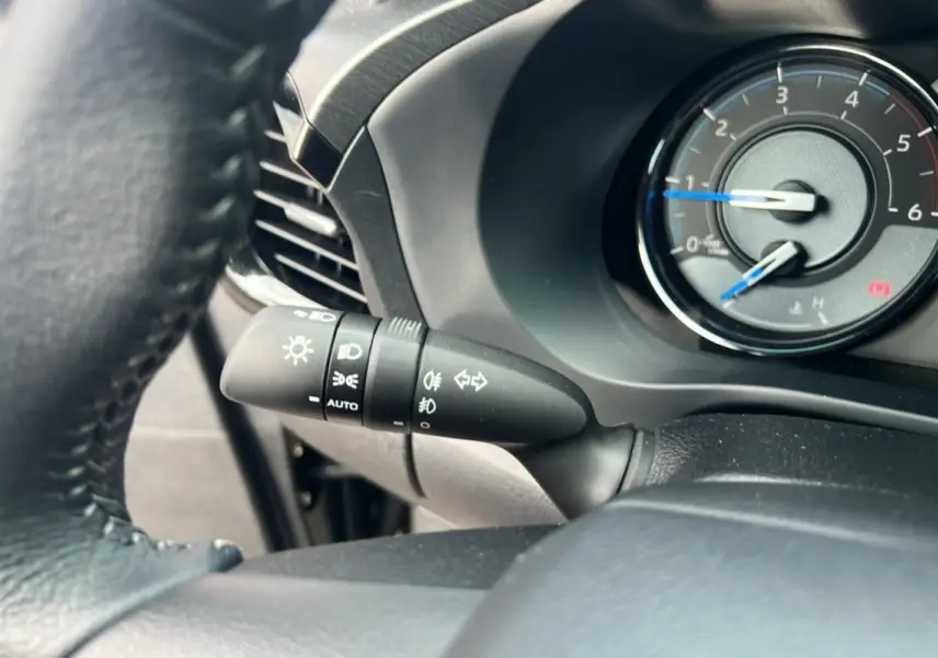 Gros plan sur la manette des phares et clignotants du Toyota Hilux 2025, intérieur noir avec compte-tours visible.