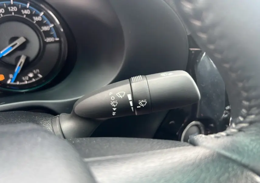 Gros plan sur la commande d’essuie-glace à gauche du volant dans le tableau de bord noir du Toyota Hilux 2025.