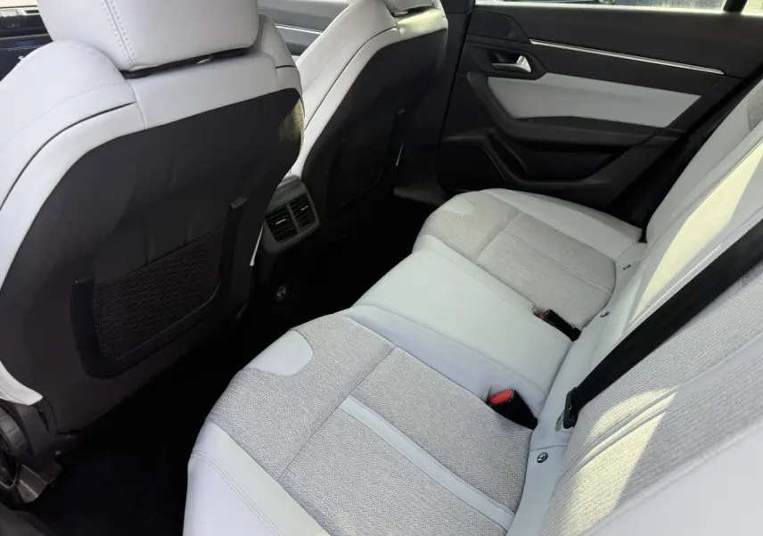 Vue intérieure arrière de la Peugeot 508 avec sièges bi-matière gris clair et aérateurs centraux visibles.
