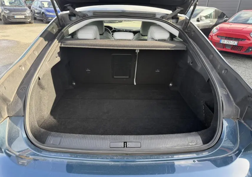 Coffre ouvert vu de l'arrière d'une Peugeot 508 bleu métallisé, montrant un espace de chargement propre et vide.