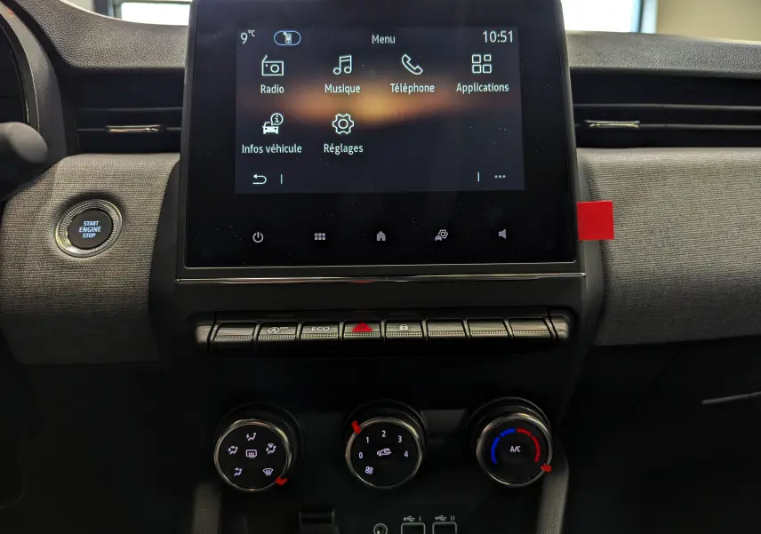 Vue rapprochée de la console centrale de la Renault Clio V gris Rafale, avec écran tactile et commandes de climatisation.