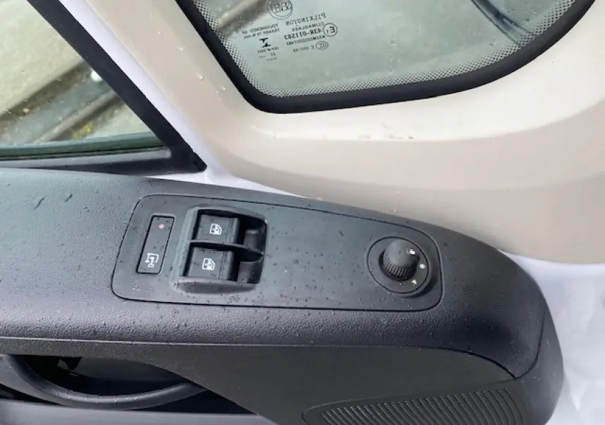 Détail de la commande des vitres et rétroviseurs côté conducteur du fourgon blanc Opel Movano 2023.