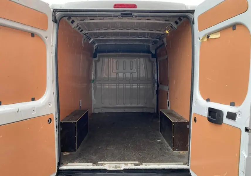 Vue arrière intérieure du fourgon blanc Opel Movano 2023 avec plancher bois et parois orange.