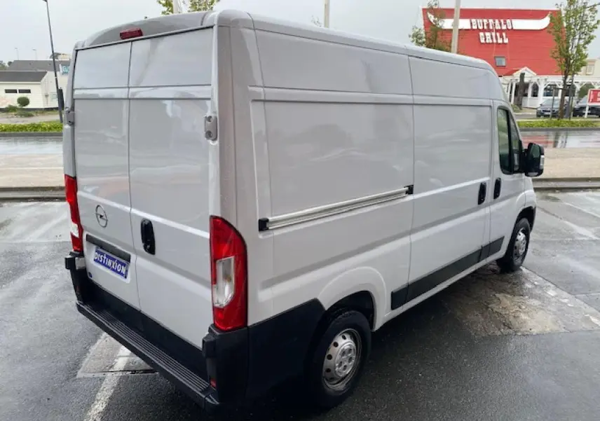Vue 3/4 arrière droite d’un Opel Movano Fourgon blanc avec porte latérale coulissante et hayon arrière fermé.