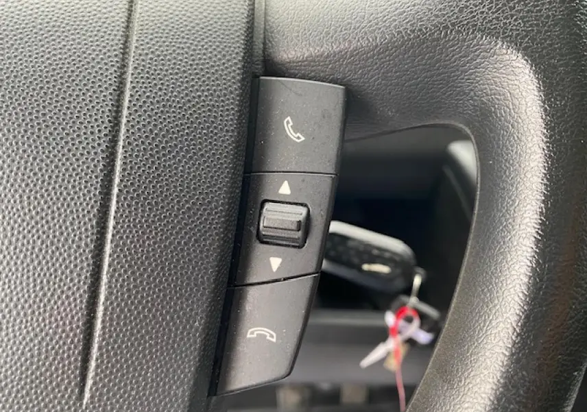 Détail des commandes Bluetooth sur le volant noir d’un Opel Movano Fourgon 2023, vue rapprochée.