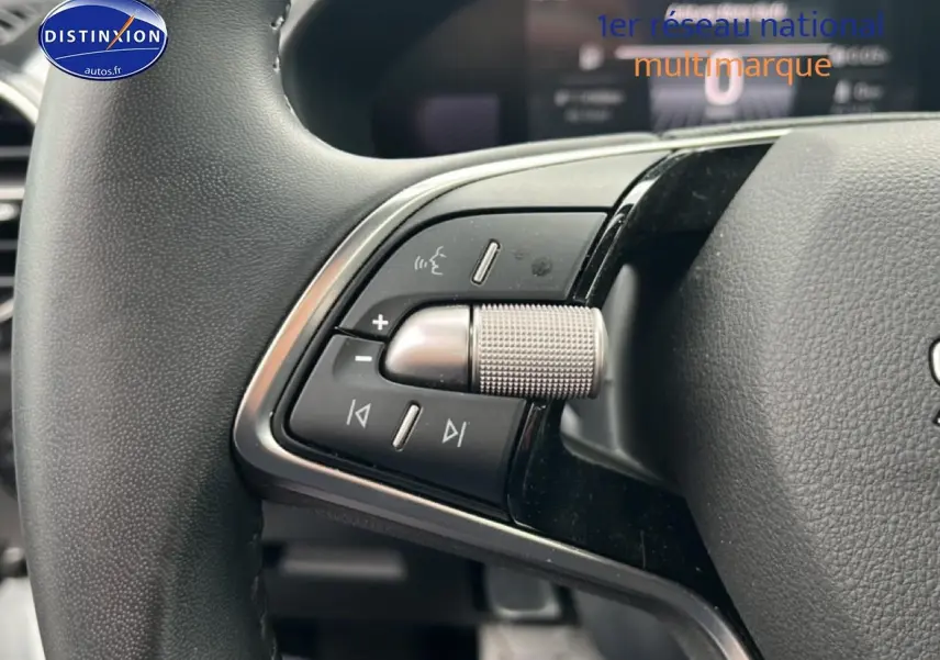 Gros plan sur les commandes multifonctions gauche du volant cuir noir de la Skoda Fabia blanche 2025.