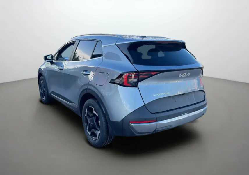 Vue 3/4 arrière gauche d'un Kia Sportage gris perle avec vitres surteintées et jantes alu 18 pouces.