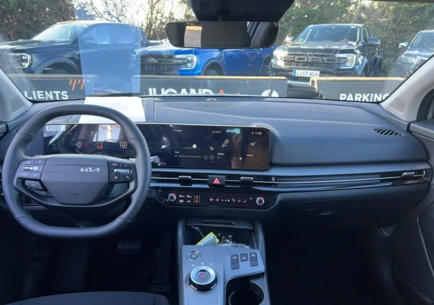 Vue intérieure avant du Kia Sportage 1.6 T-GDI HEV 239 EX 2026, tableau de bord moderne avec écran large et volant multifonctions.