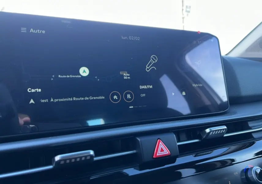 Vue rapprochée de l'écran tactile central et des commandes de ventilation du tableau de bord du Kia Sportage gris perle 2026.