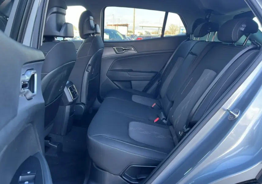 Vue intérieure arrière côté droit du Kia Sportage gris perle 2026, montrant la banquette tissu et les appuie-têtes.