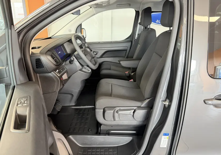 Vue intérieure côté conducteur du Citroën Jumpy gris titane, montrant les sièges avant et le tableau de bord.