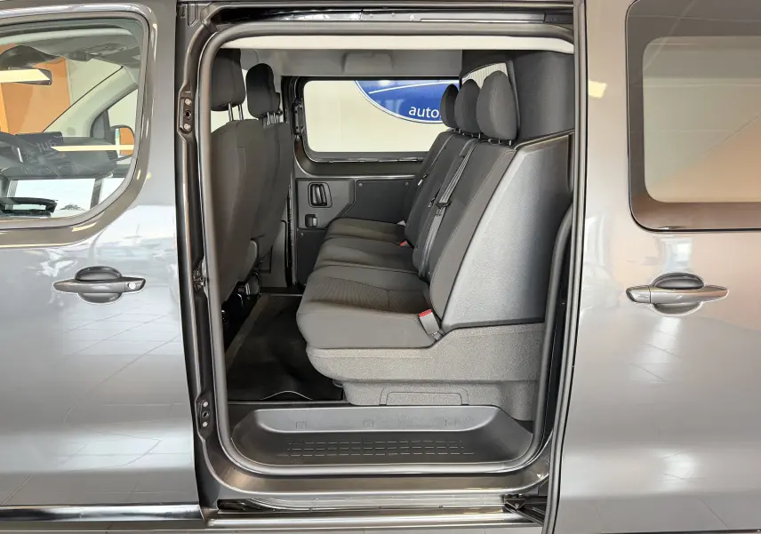 Vue latérale intérieure du Citroën Jumpy gris titane, montrant la banquette arrière 3 places et la porte coulissante ouverte.