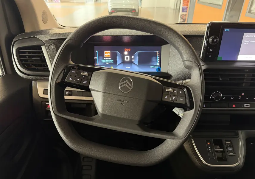 Vue intérieure centrée sur le volant multifonction noir et le combiné numérique du Citroën Jumpy Cabine Approfondie gris titane.