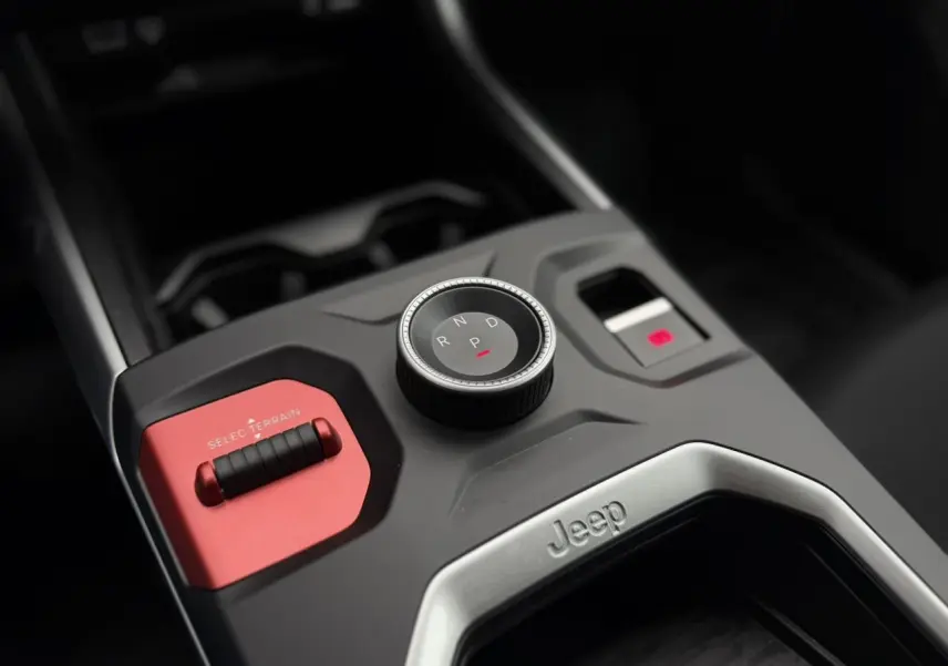 Gros plan sur la console centrale du Jeep Compass Hybrid 2026, avec molette de boîte auto et bouton Selec Terrain rouge.
