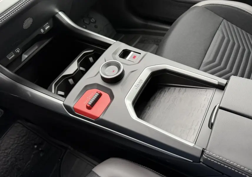 Vue rapprochée de la console centrale noire du Jeep Compass Hybrid 2026 avec molette de sélection et insert rouge distinctif.