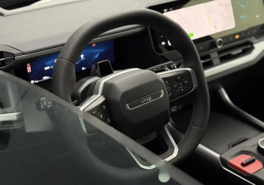 Vue rapprochée du volant noir du Jeep Compass 2026 avec tableau de bord numérique et écran tactile central.