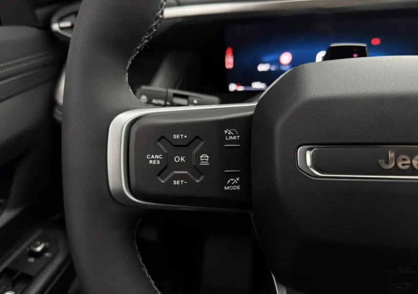 Gros plan sur le volant noir du Jeep Compass 2026, mettant en valeur les commandes du régulateur adaptatif côté gauche.