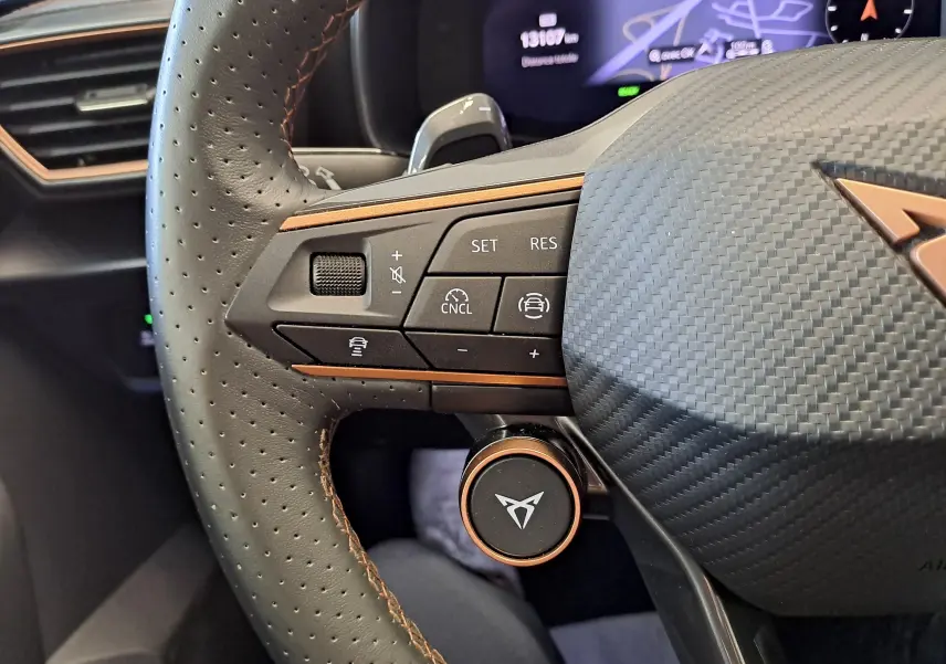 Gros plan sur le volant perforé noir avec surpiqûres cuivrées et commandes intégrées du CUPRA LEON ST 1.5 eTSI 2025.