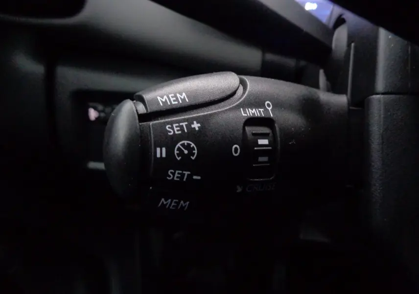 Gros plan sur la commande de régulateur de vitesse noire dans l'habitacle d'une Citroën C5 Aircross gris Artense métal.